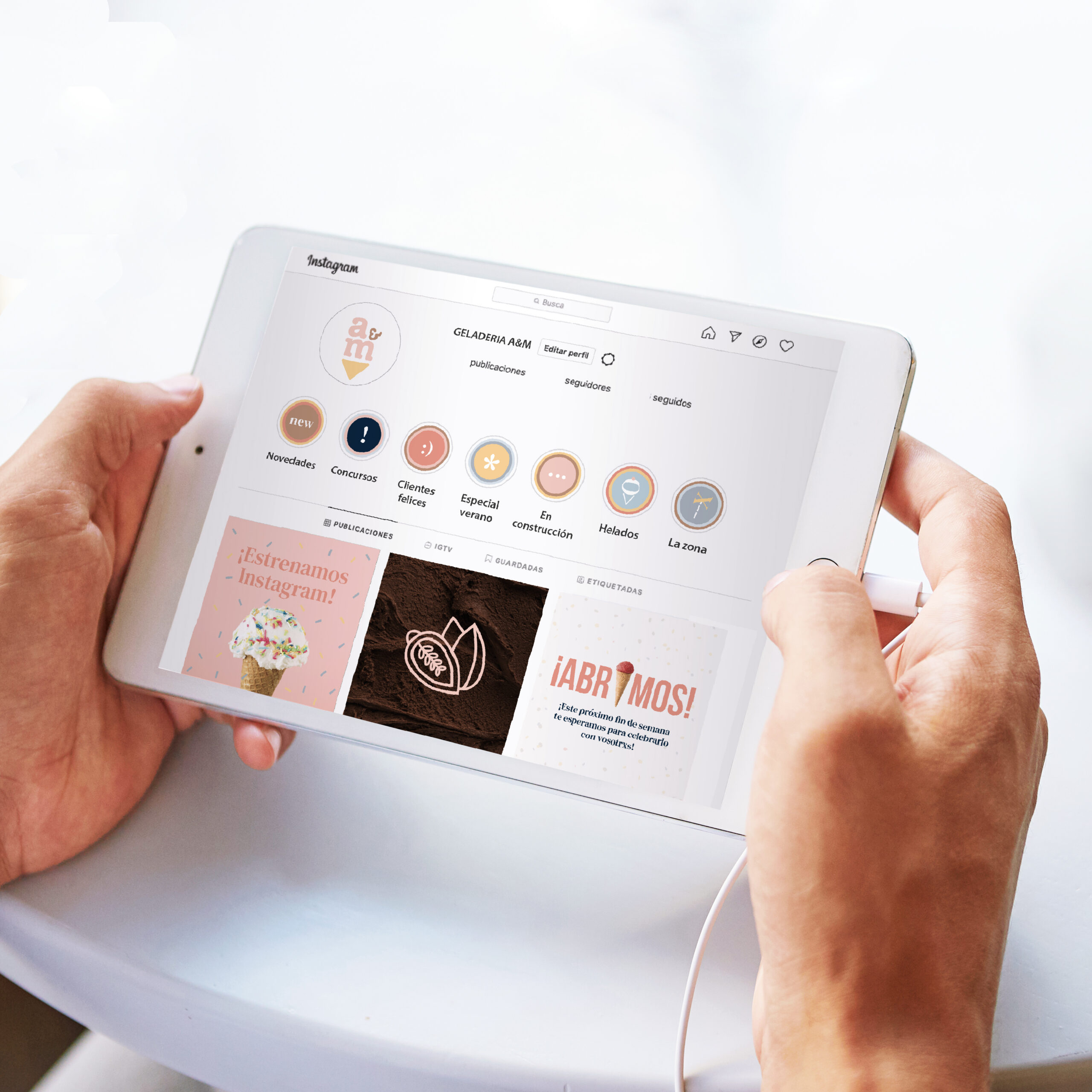 Indoor close-up of man's hands holding tablet with plugged earphones, having lunch break with cup of coffee, keeping smartphone on table